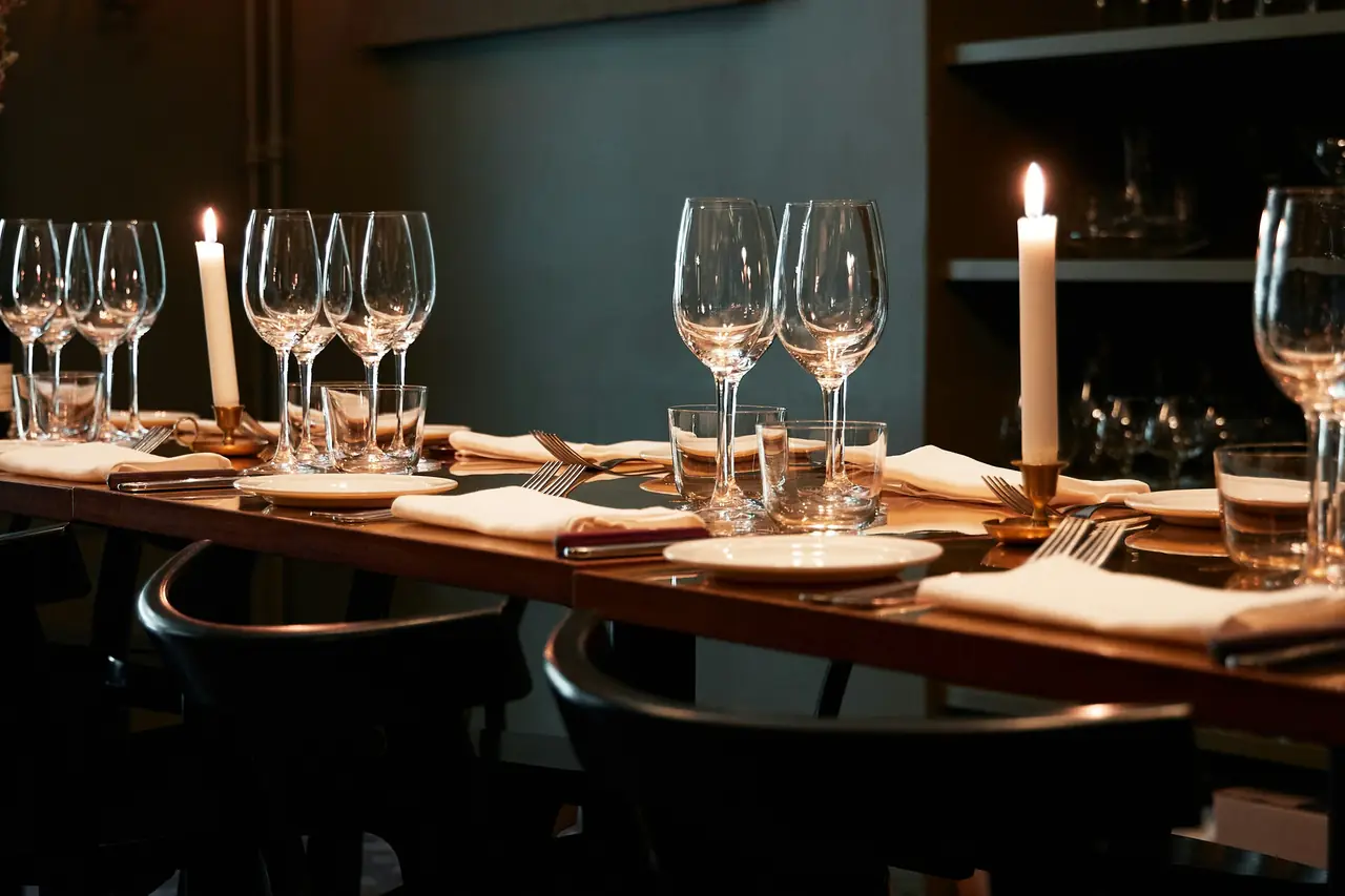 Mesa formal tendida con copas de vino y velas encendidas, lista para el servicio.