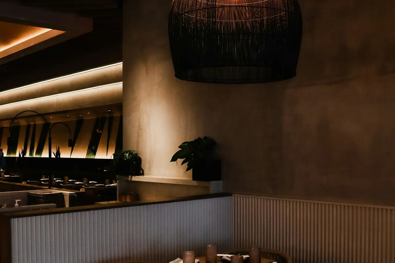 Comedor de muros de estuco cálido con una lámpara de mimbre suspendida sobre la mesa.