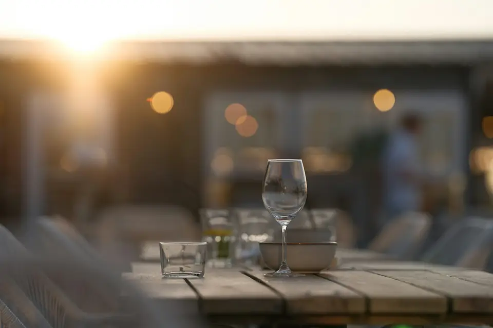 Copa servida en una mesa de terraza, recortada contra el sol bajo del atardecer.